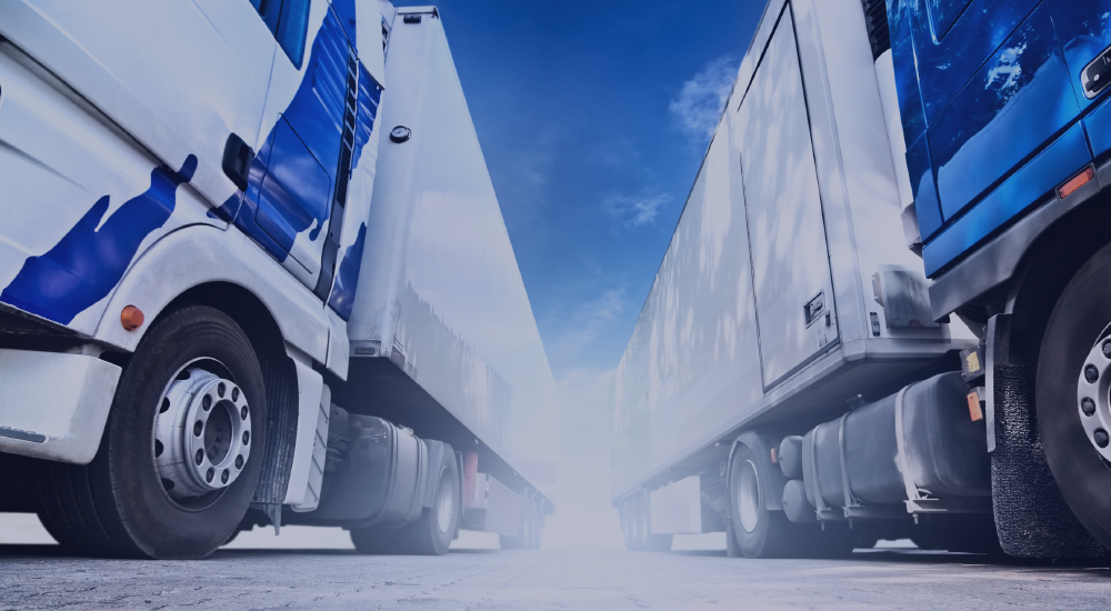 An image taken from the floor angle pointing upwards of two white and blue trailer trucks parked next to each other with a big sun glare inbetween them.
