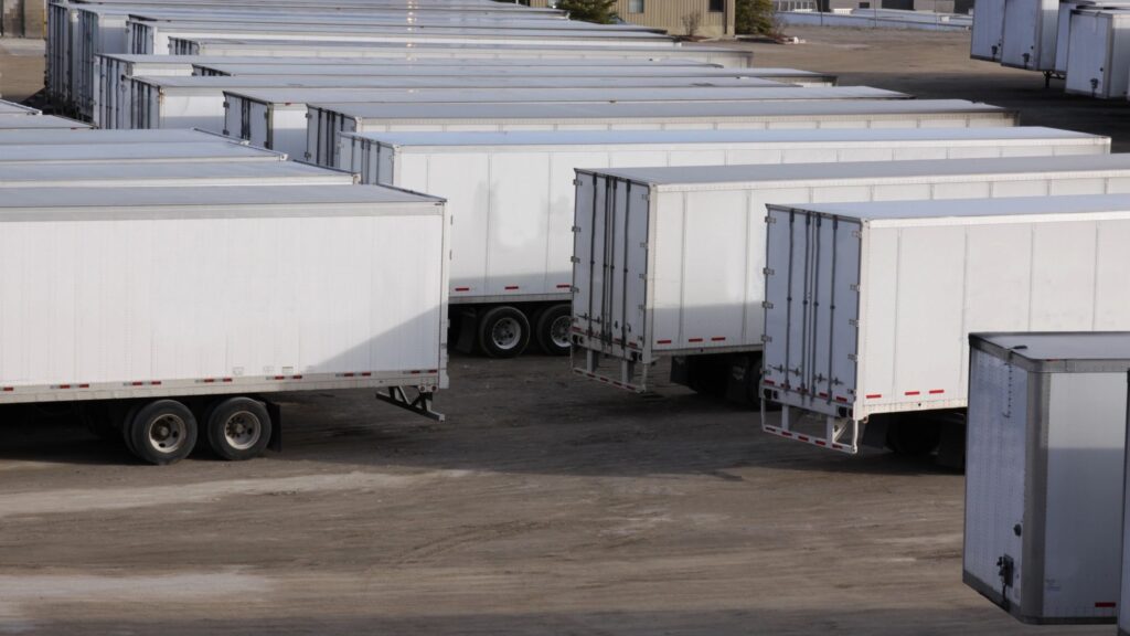 White trailer fleets parked in a transportation parking hub, side by side.